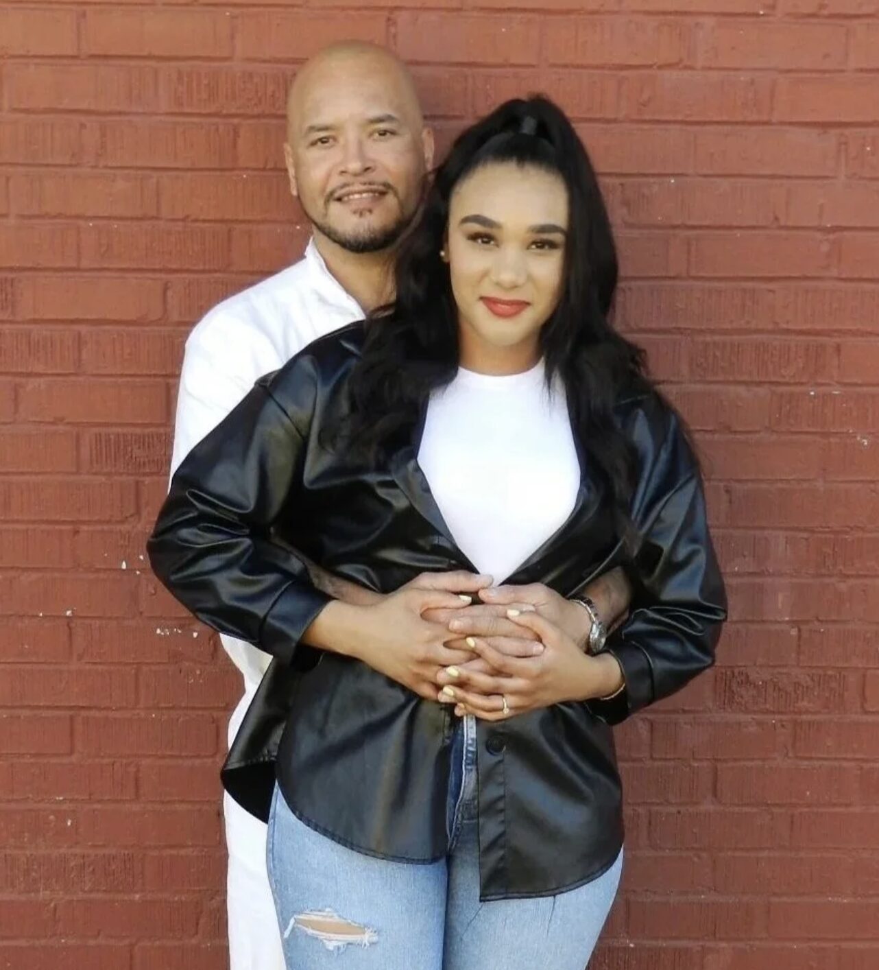Nanon and his wife, Tera Warner, in front of a red brick wall.